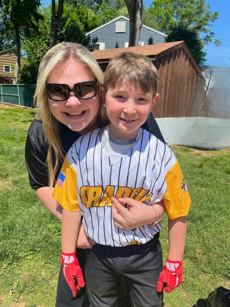 Mom hugging child in baseball uniform