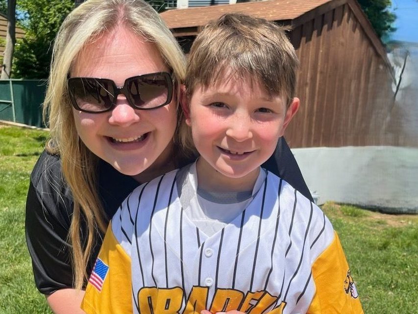 Mom hugging child in baseball uniform